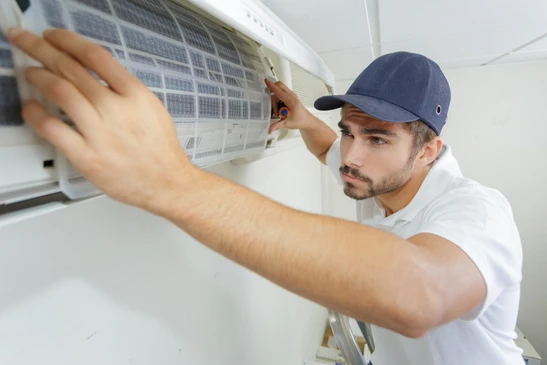 Technicien en climatisation effectuant la maintenance d'une unité murale intérieure