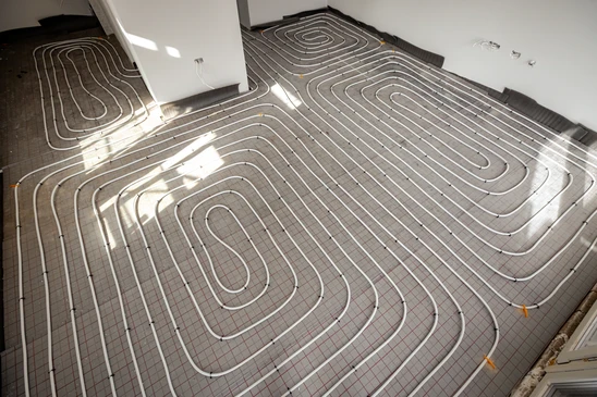 Intérieur moderne avec sol en parquet bois clair partiellement soulevé révélant l'installation de chauffage au sol