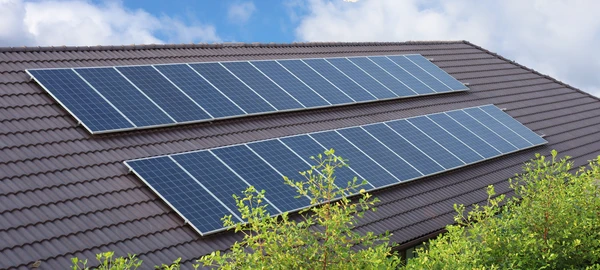 Deux techniciens installent des panneaux solaires photovoltaïques sur une toiture résidentielle en tuiles